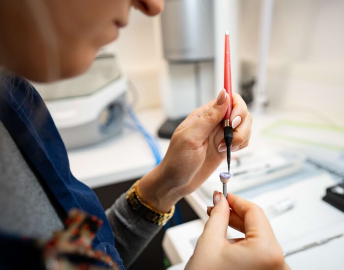 Eine Mitarbeiterin bearbeitet ein Zahnimplantat im Labor.