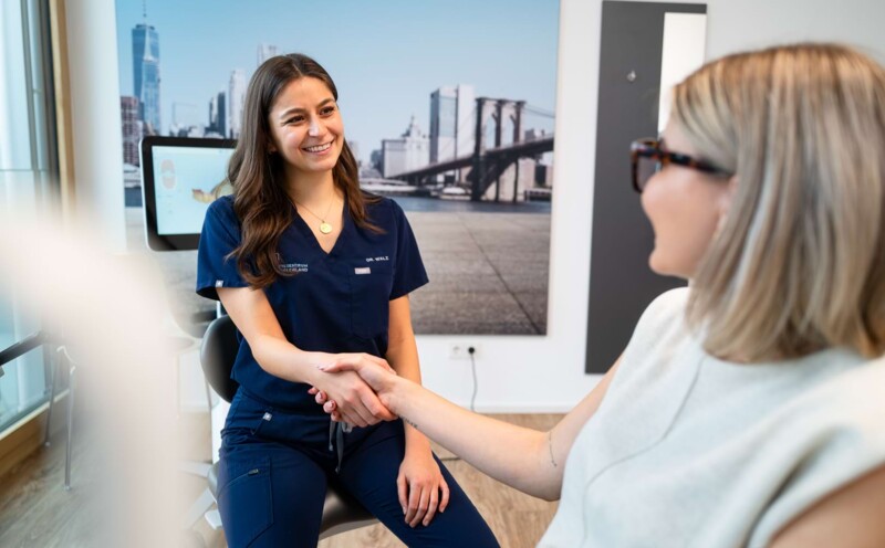 Eine Behandlerin begr&uuml;&szlig;t herzlich eine Patientin.