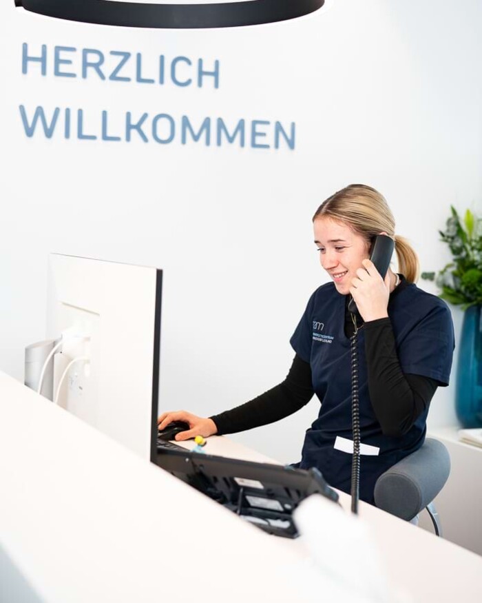 Eine Mitarbeiterin am Empfang ist gerade im Telefonat.