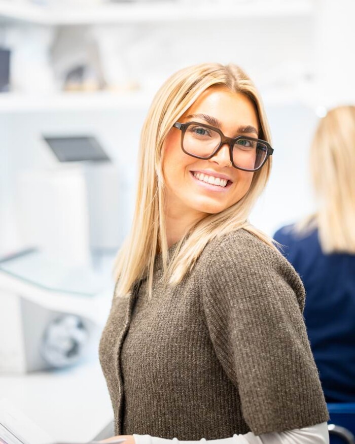 Eine Mitarbeiterin schaut lachend in die Kamera.